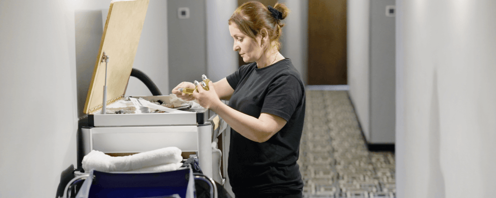 Hotel cleaner gets additional supplies from cart